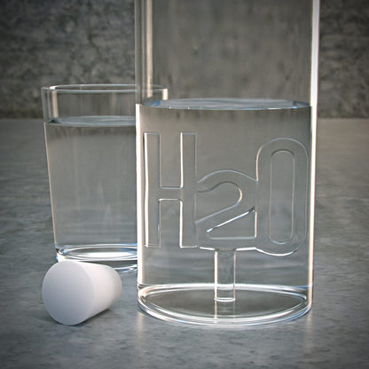 Atlantis H2O bottle beside an empty glass containing a lilac shell