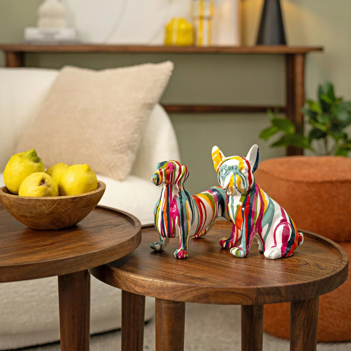 The Bulldog Pop figure alongside another striped dog figure, on two wooden side tables with a bowl of fruit.