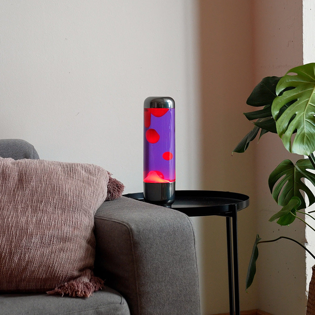 Lampada da Tavolo Lava Capsule: la lampada accesa viola e rossa su un tavolino da salotto.