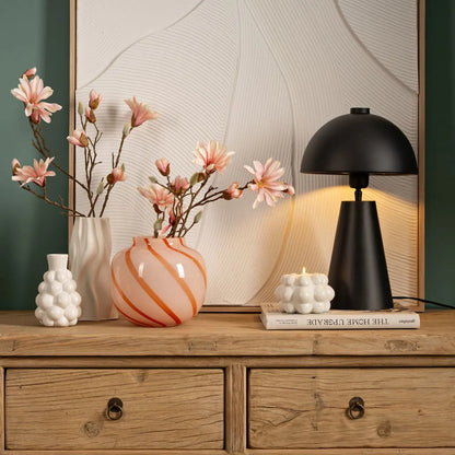 Candy Stripe vase in orange and white stripes, on a dresser among other flower vases.