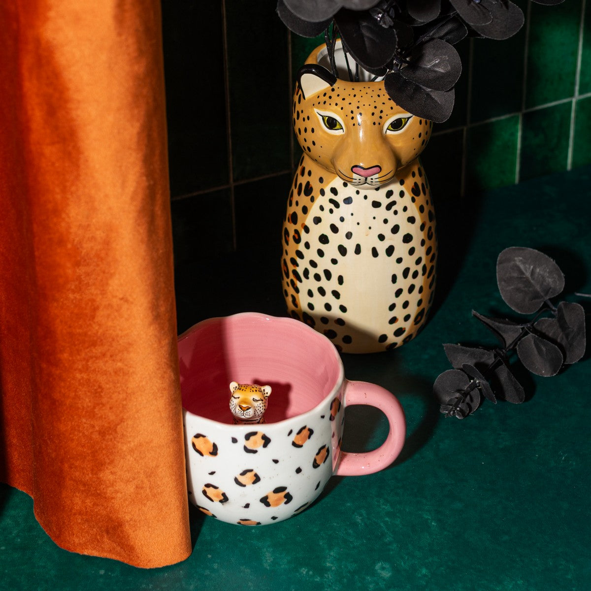 Leopardo vase shaped like a leopard, next to a leopard-print mug with a pink interior.