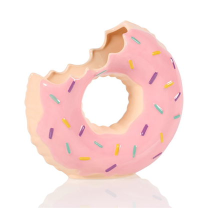 Doughnut vase in pink with a bite taken out and colourful sprinkles, empty on a white background.