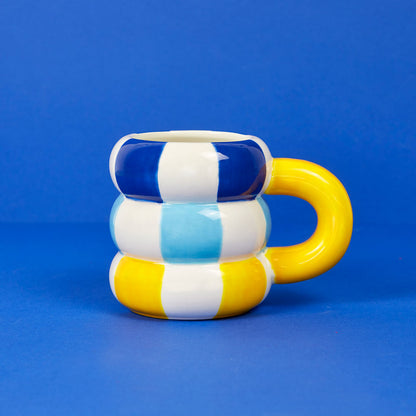 Floats Gialla mug in blue, white and yellow stripes with a yellow handle on a blue background