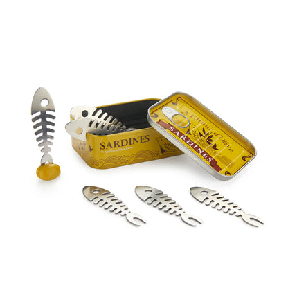 Fish-bone shaped cocktail forks, shown inside and around a sardine-tin style box.