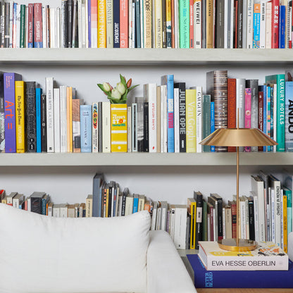 Yellow Book vase with tulips, barely visible among the books of a large bookcase