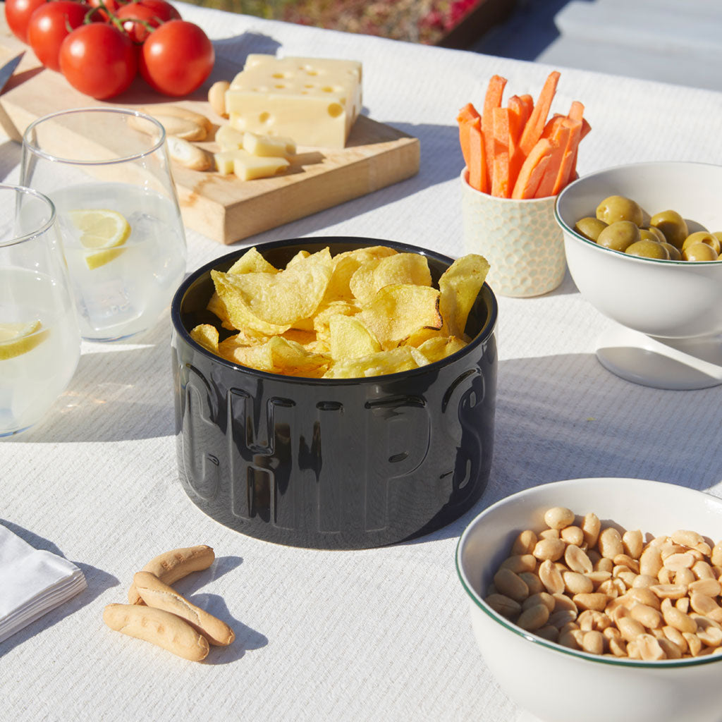 Ciotola Snack Chips nera su una tavola apparecchiata con pomodori, formaggio, carote e olive