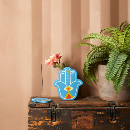 Blue Lucky Hand vase with a pink flower on a wooden trunk