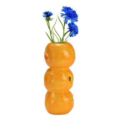Oranges vase with a bunch of blue cornflowers placed on top.