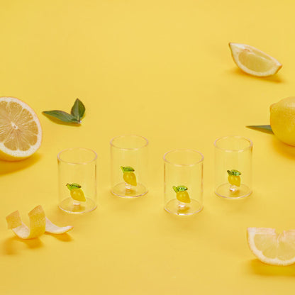 Lemon liqueur glasses on a yellow background, surrounded by real lemons and peel