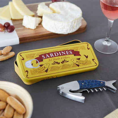Sardines corkscrew on a board with cheese, wine and the open yellow sardine tin.