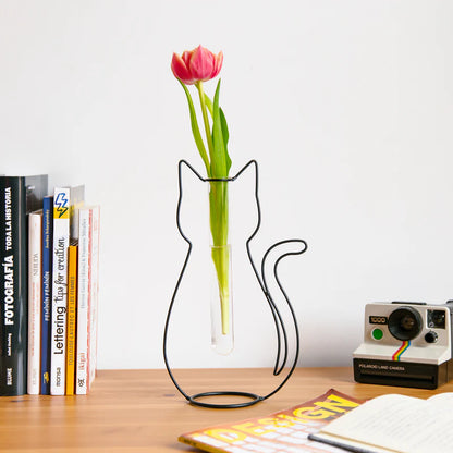 Cat Silhouette vase with a pink tulip on a desk among books and a camera