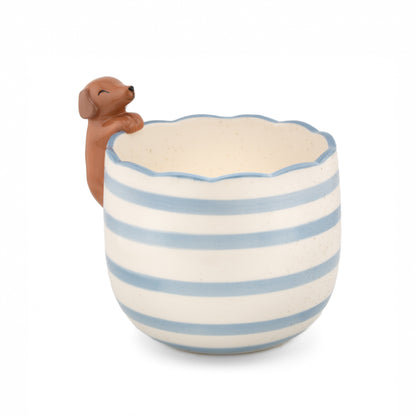 Vaso Bassotto Curioso: un cagnolino di ceramica marrone che sbircia dal bordo di un vaso a righe azzurre e bianche.
