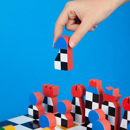 A hand holds a red and blue bishop above the chessboard, on a blue background