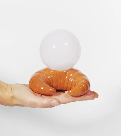 The croissant lamp held in one hand, to show its size