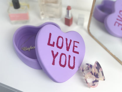 Love You heart box in lilac, open on a dressing table, with lipstick in the background.