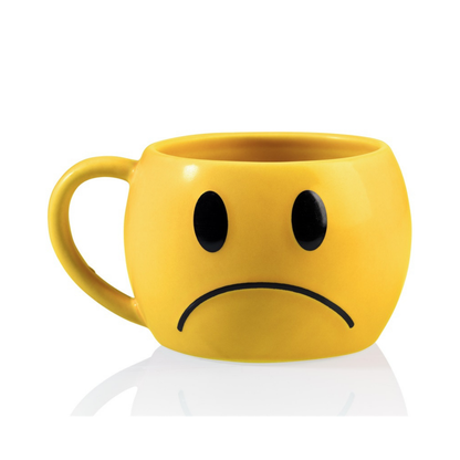 The matching yellow mug with a sad face, downturned eyes and mouth