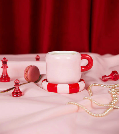 Love mug in white on pink fabric surrounded by chess pieces, pearls and a macaron