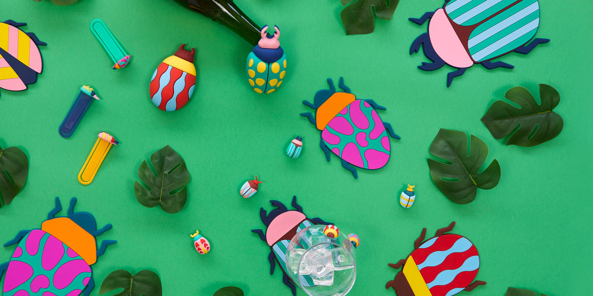 Colourful beetles: coasters and tableware on a green background among monstera leaves